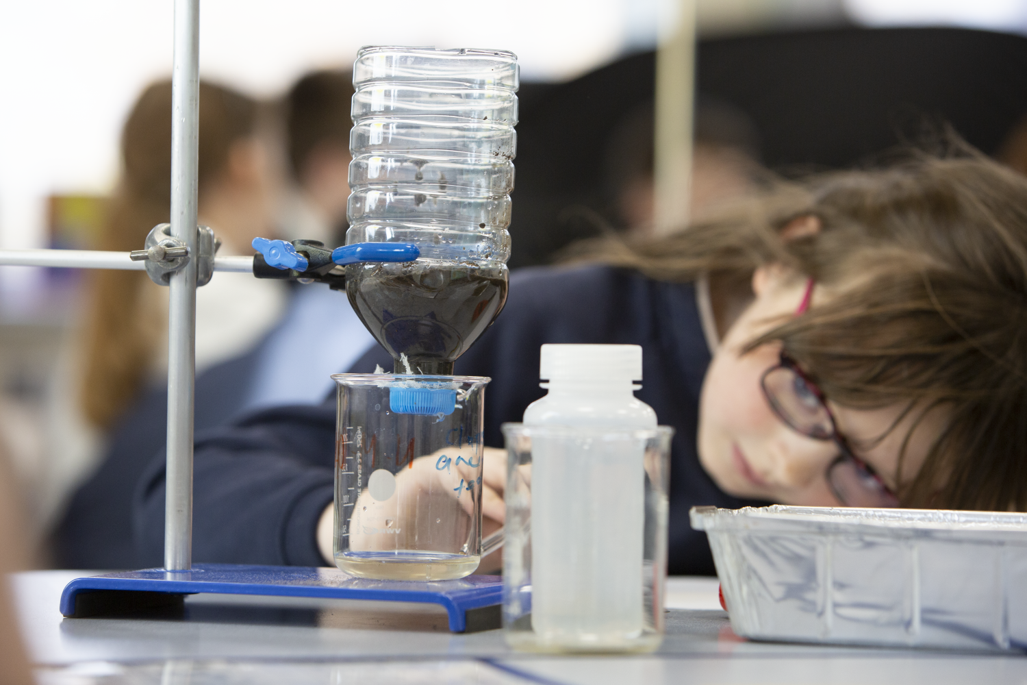 Image shows a young female student peering at science apparatus, having a go at soil testing during the Hub's KATS programme